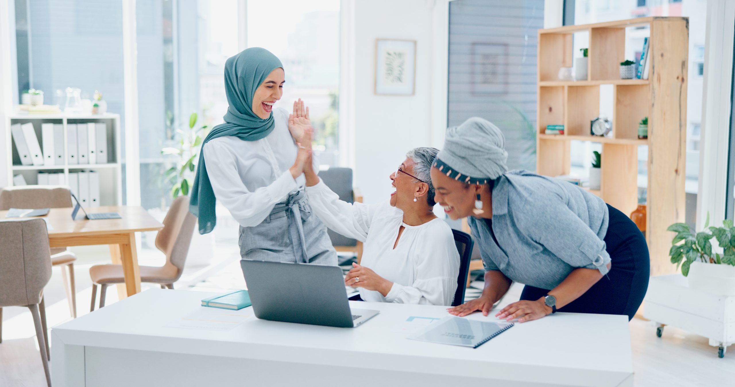 Creative business people, laptop and applause for good news, email or market sale in startup at the.