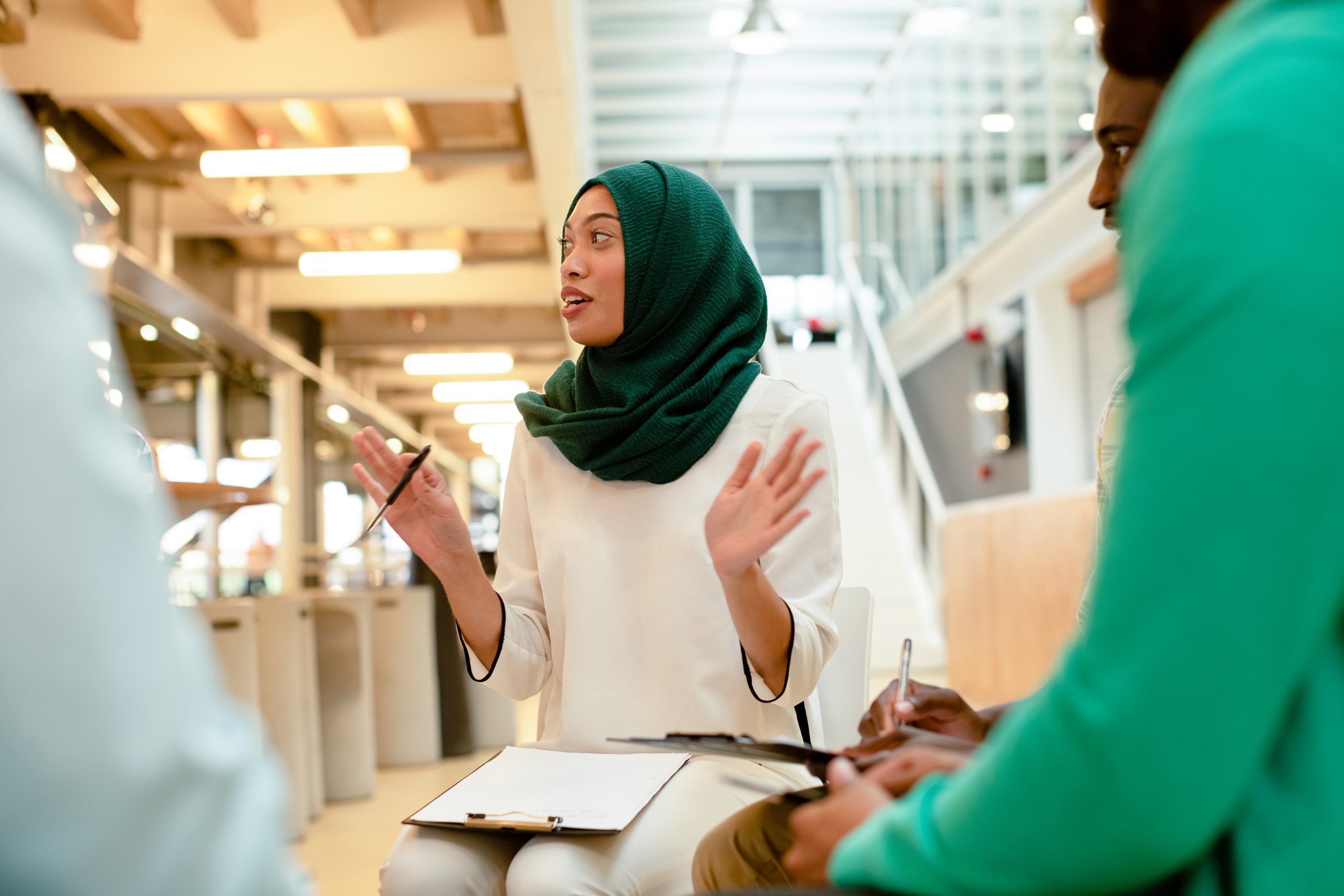 Front view of diverse business people sitting together and having a group discussion in a modern office